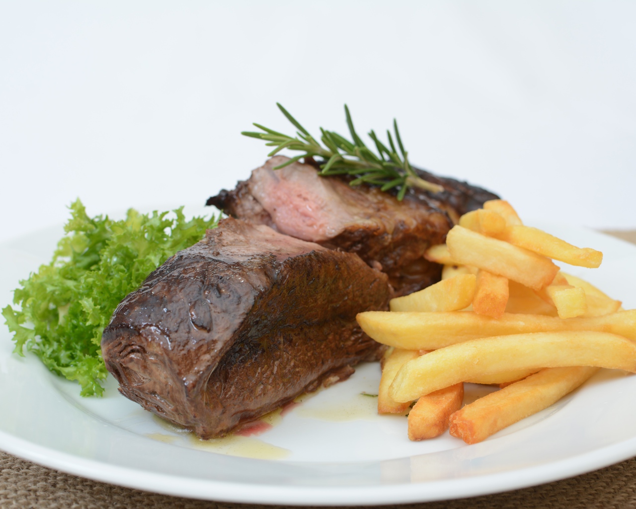 Два куска мяса на тарелке с картофелем фри 