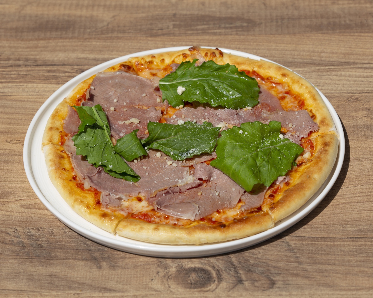 Пицца с кусочками мяса и зеленью на столе