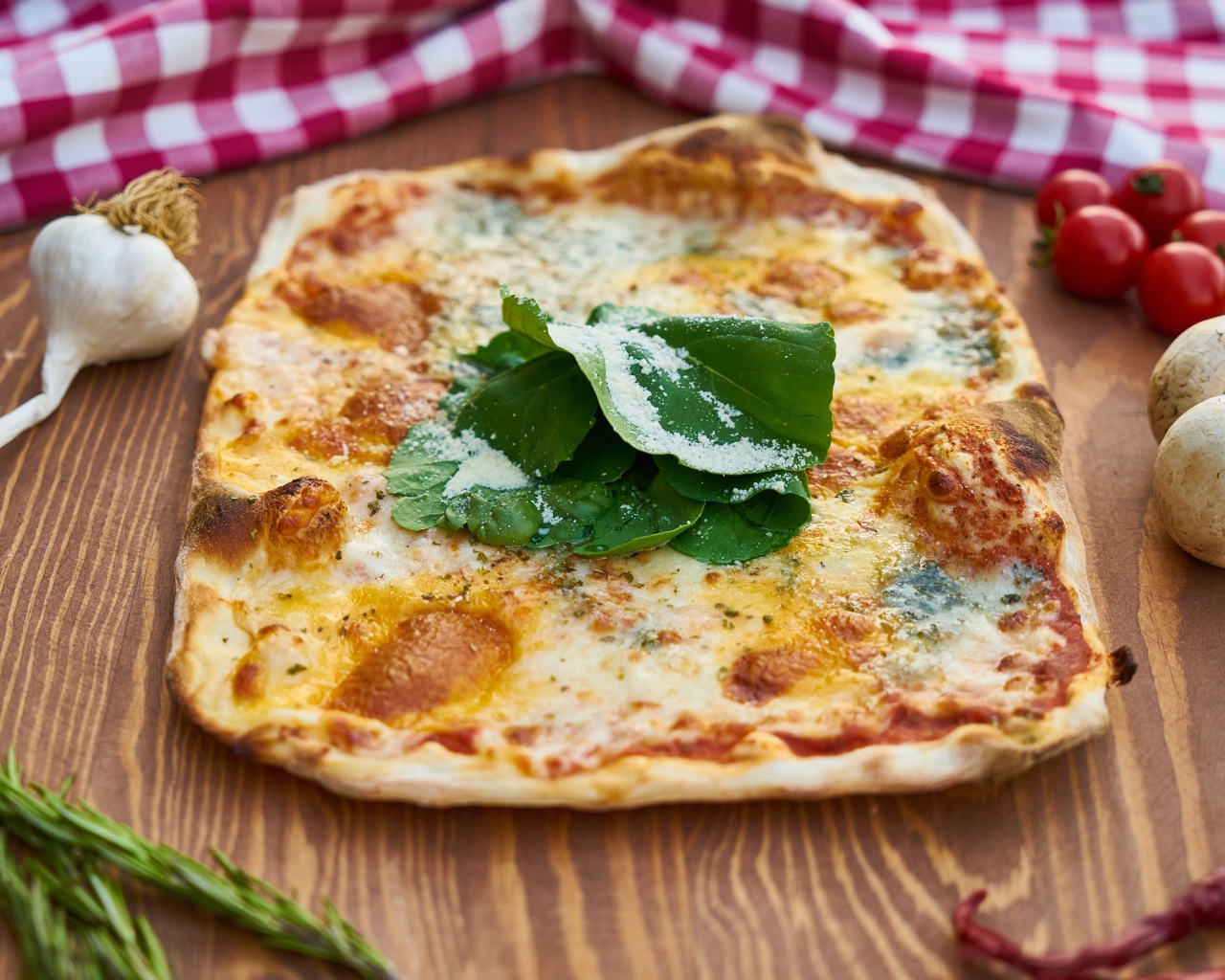 Румяная пицца на столе с овощами