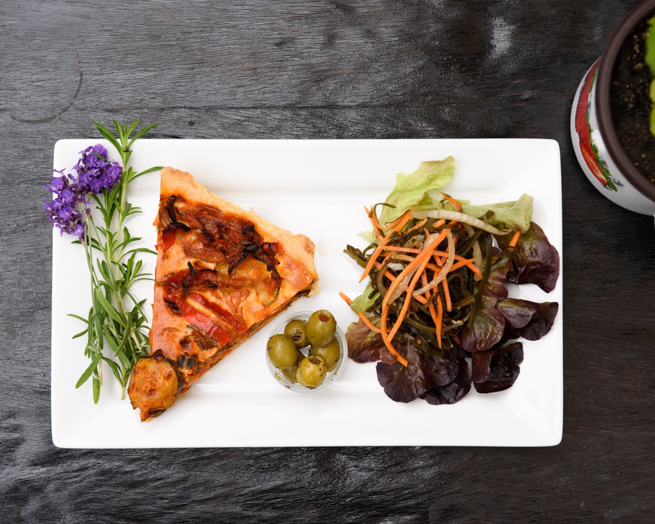 Кусок пиццы с салатом и оливками на белой тарелке