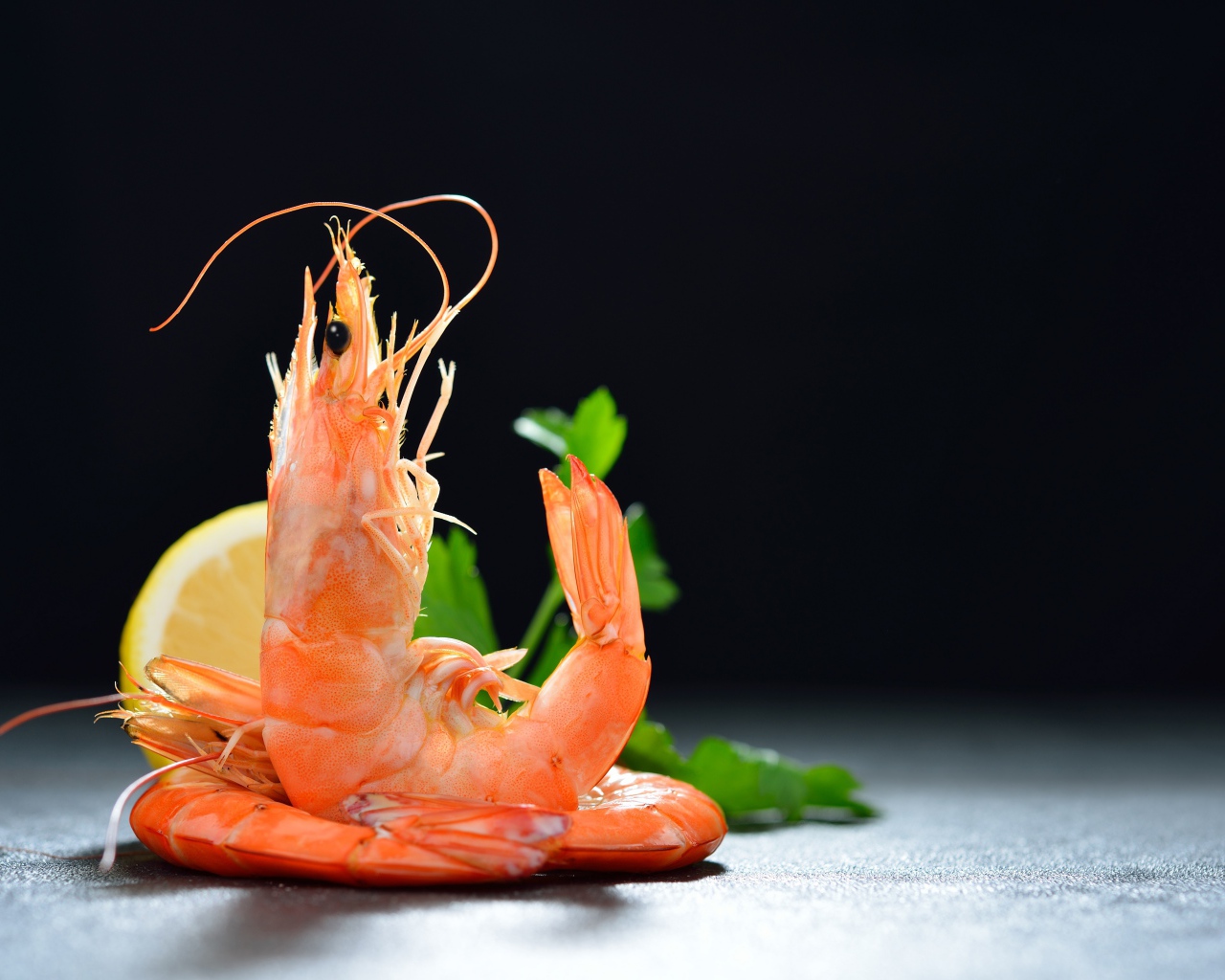 Вареные креветки с лимоном на черном фоне