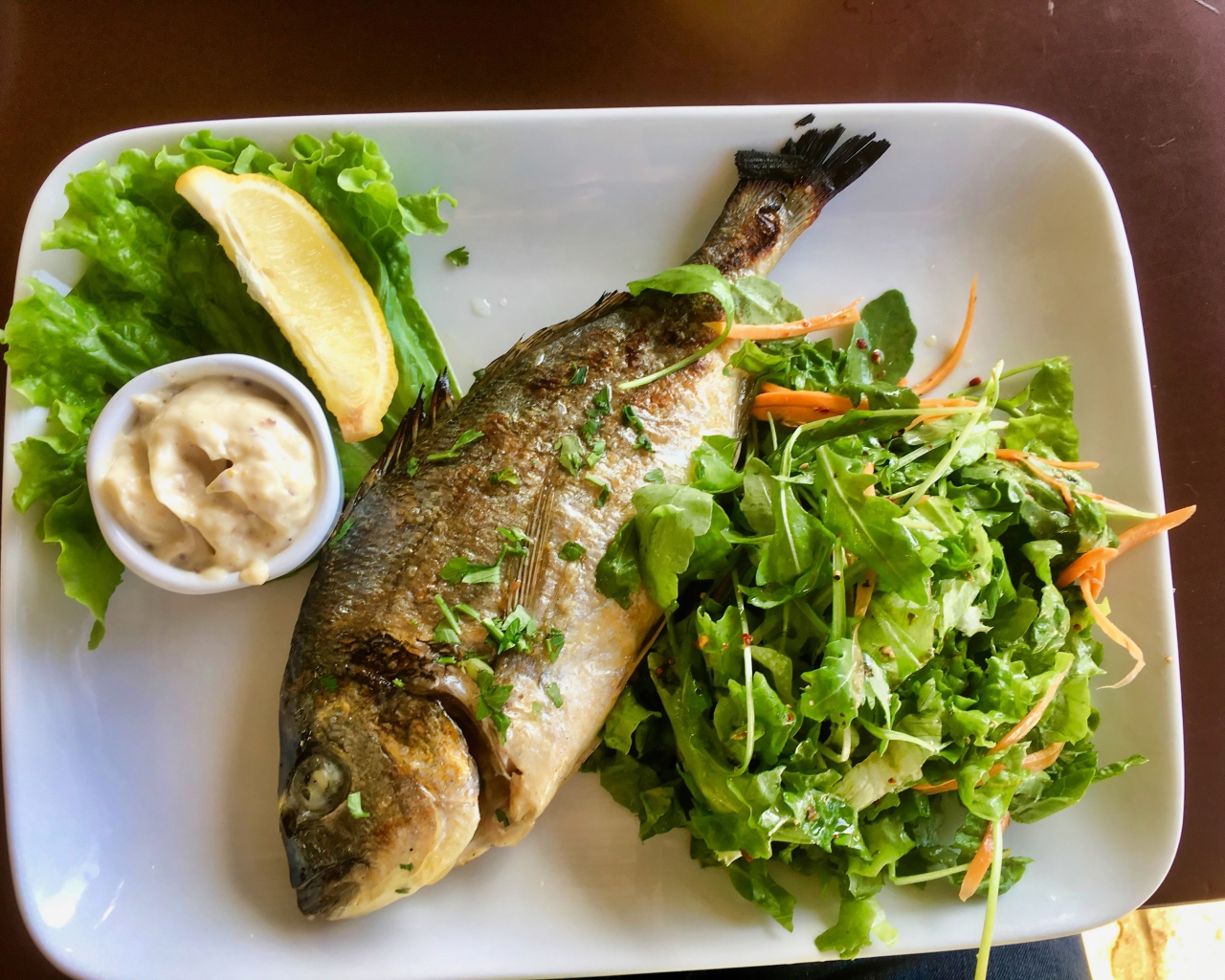 Жареный карась на тарелке с салатом 