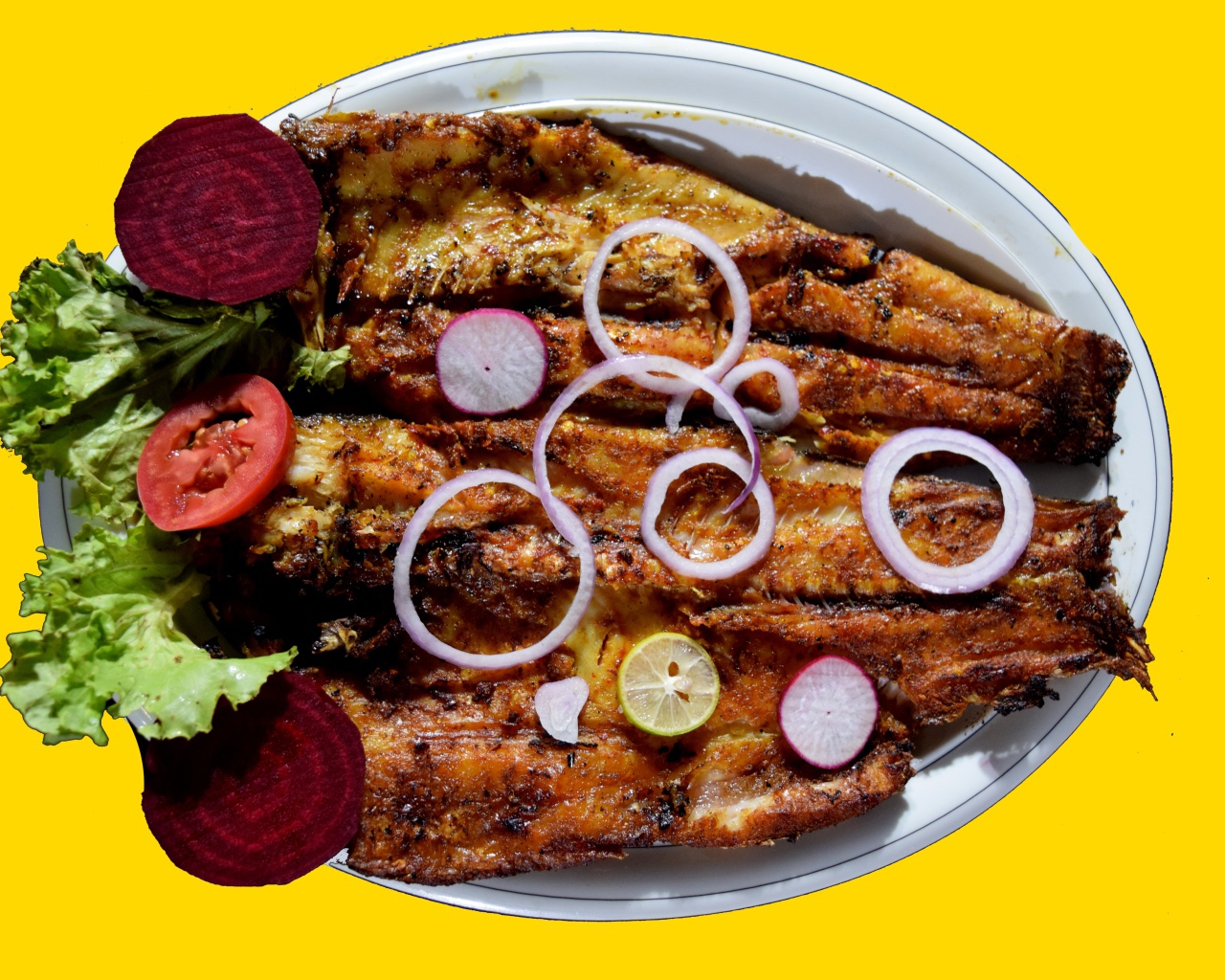 Жареная рыба с листьями салата, помидорами и свеклой на желтом фоне