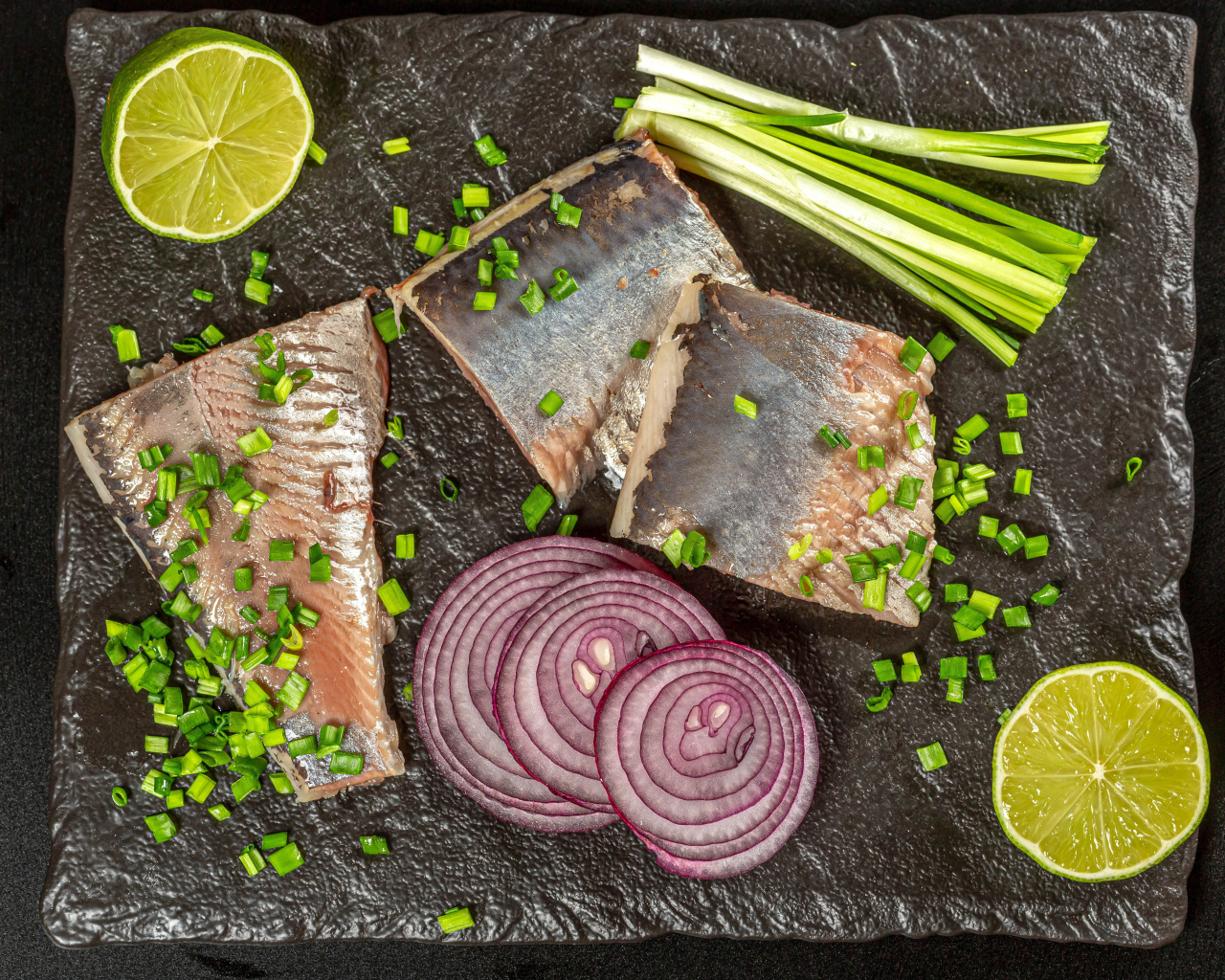 Куски сельди с луком и кусочками лимона