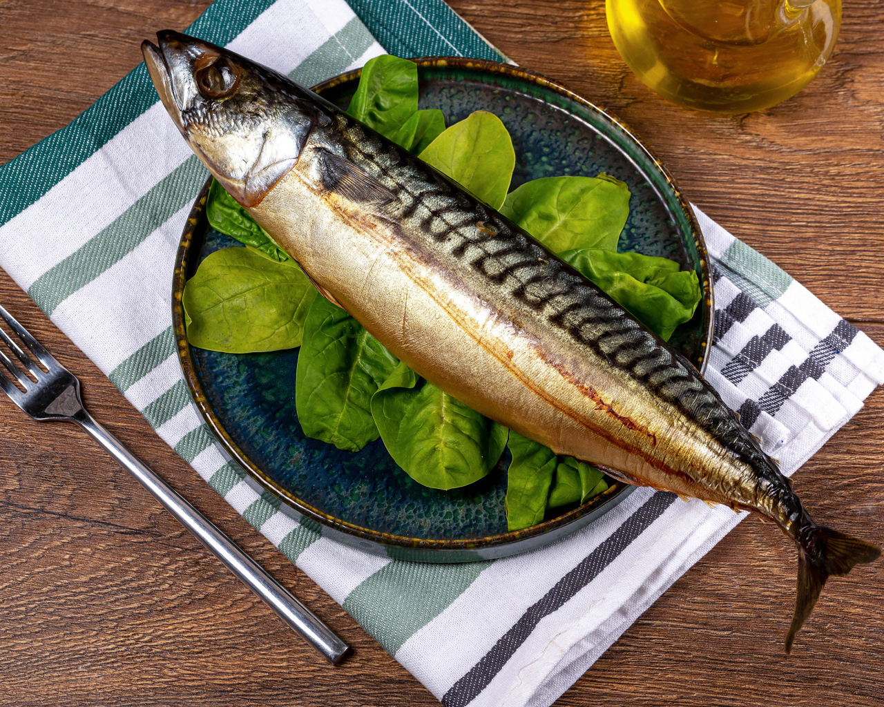 Большая жирная скумбрия на тарелке с базиликом