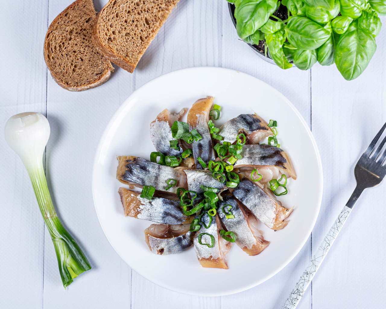 Куски скумбрии на столе с луком, хлебом и базиликом