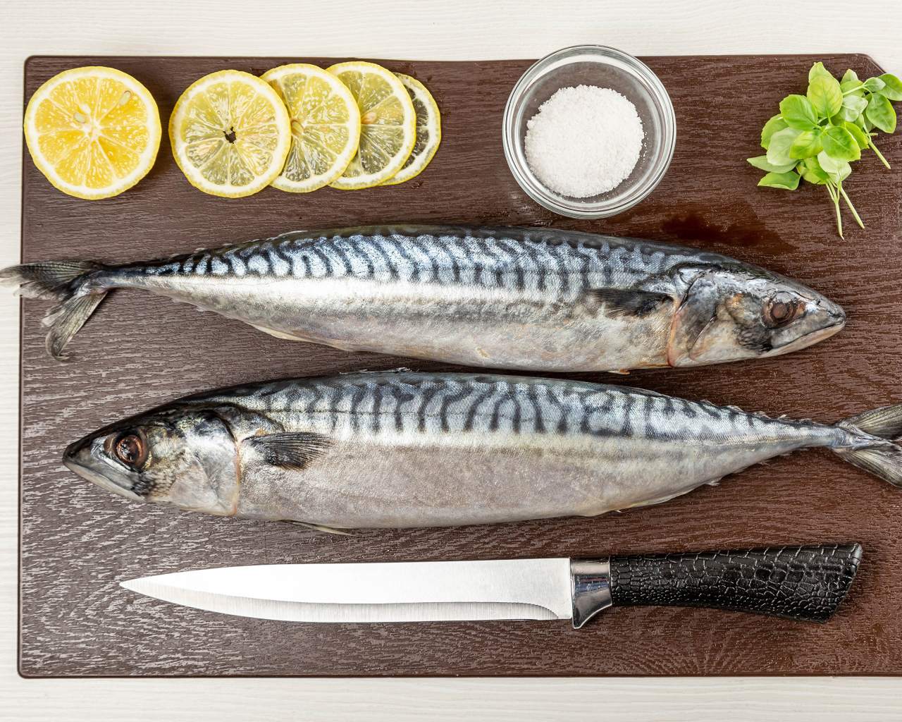 Две свежие скумбрии на доске с лимоном 