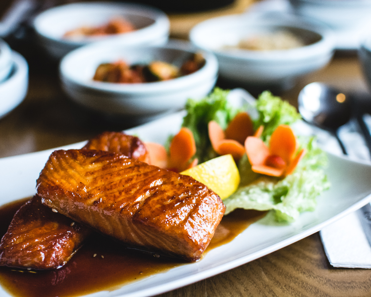 Два куска рыбы в соусе с овощами на тарелке