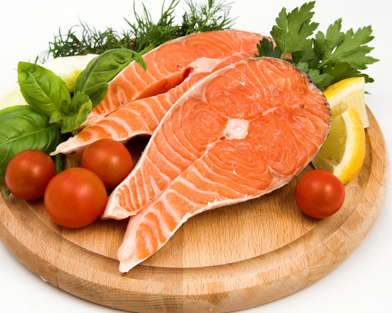 Два куска красной рыбы на доске с зеленью и помидорами