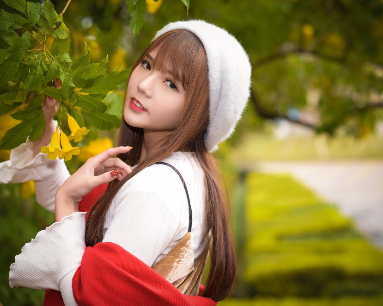 Девушка в берете стоит у куста с желтыми цветами