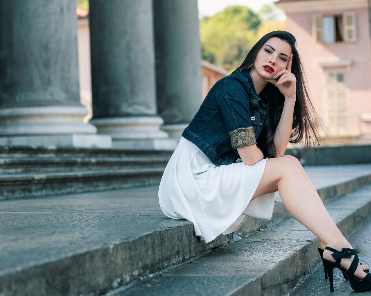 Девушка в белом платье сидит на ступеньках
