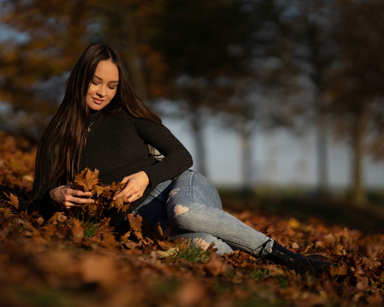 Молодая девушка лежит на опавшей листве