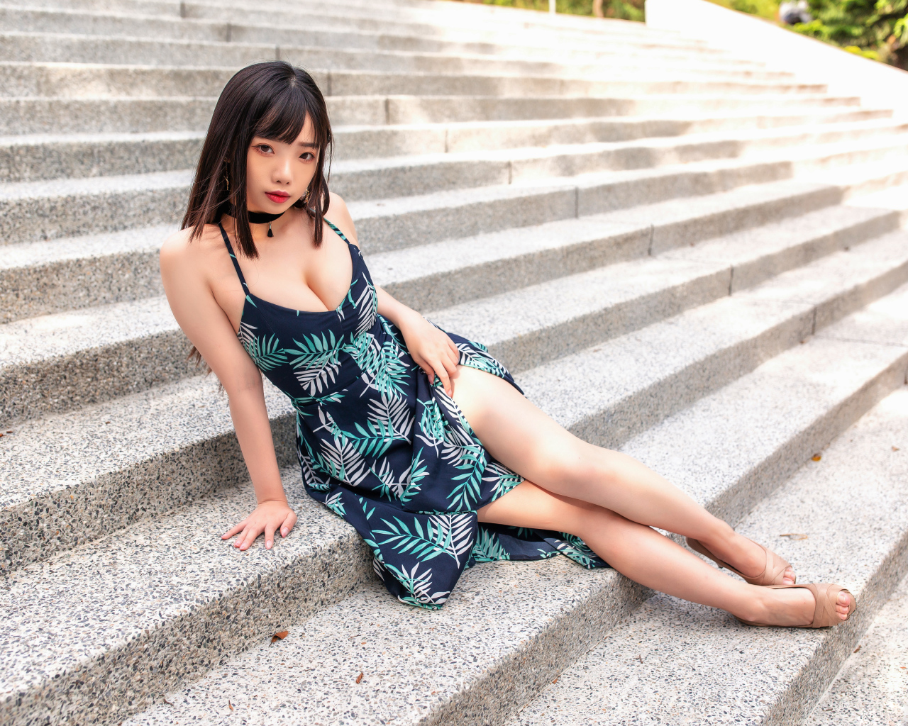 Девушка азиатка в платье сидит на ступеньках