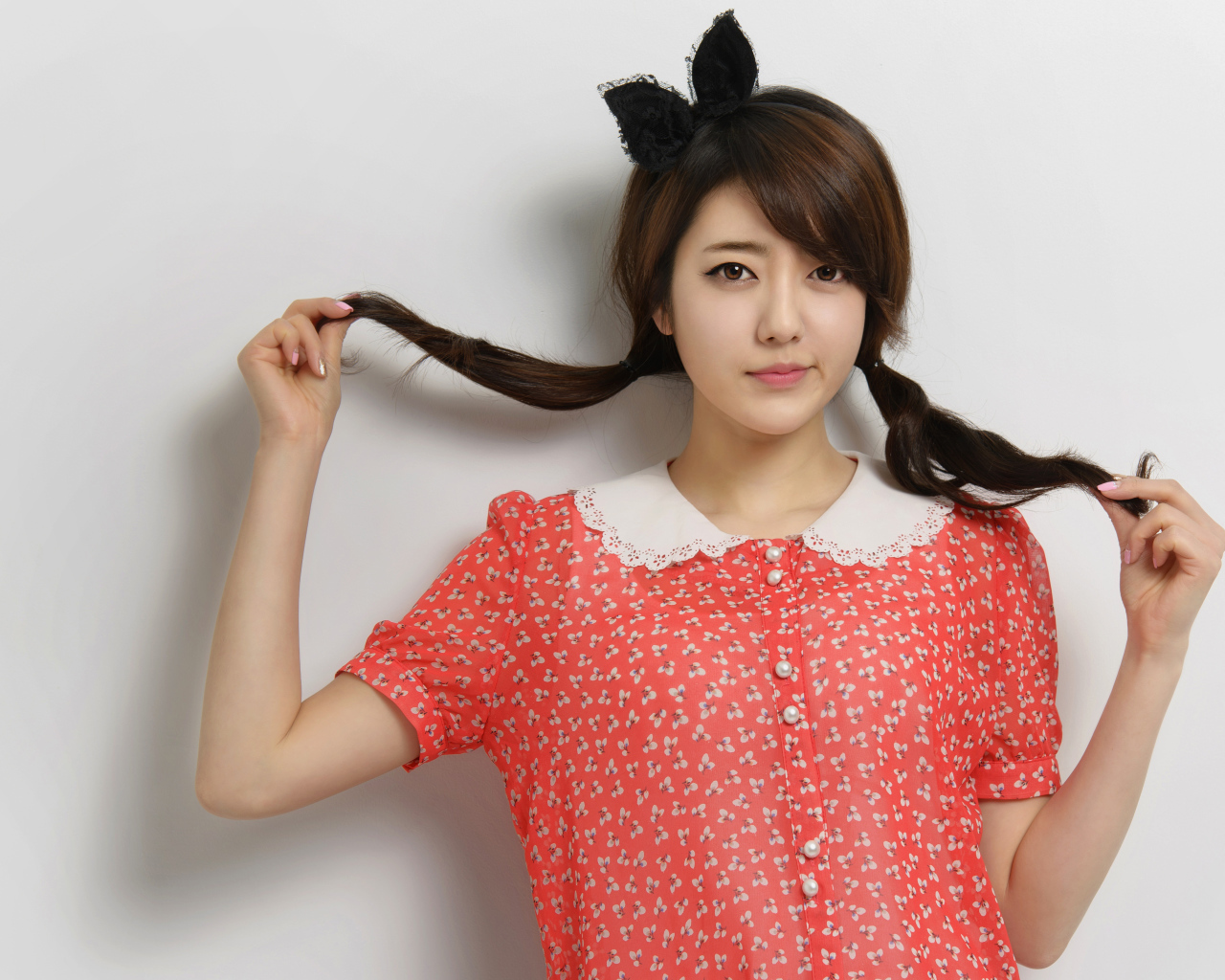 Девушка азиатка в платье стоит у стены 