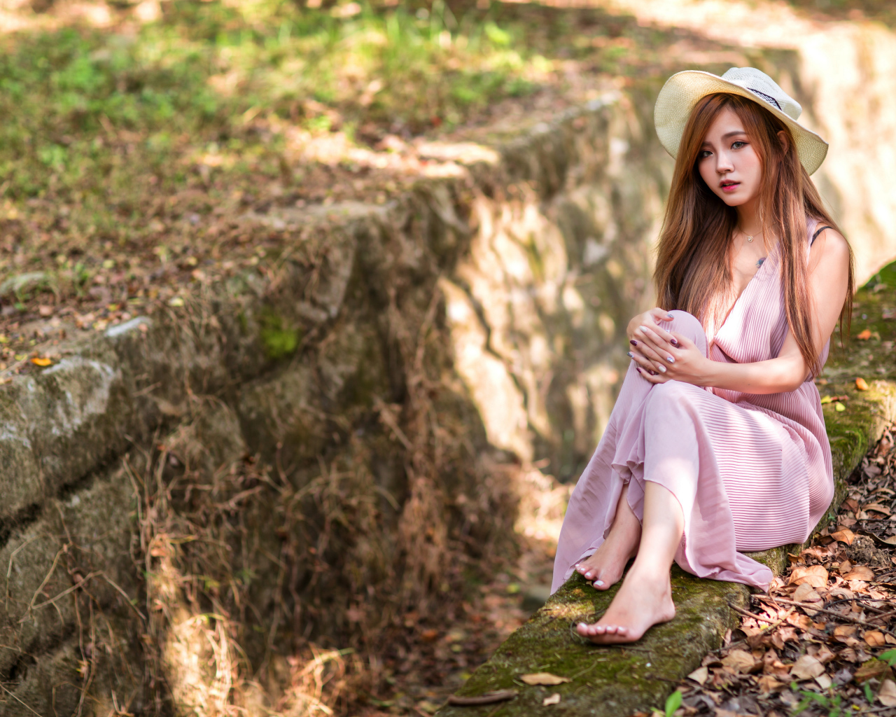 Девушка азиатка в розовом платье сидит на земле