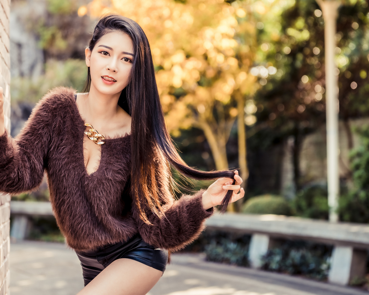 Девушка азиатка в черных шортах у стены