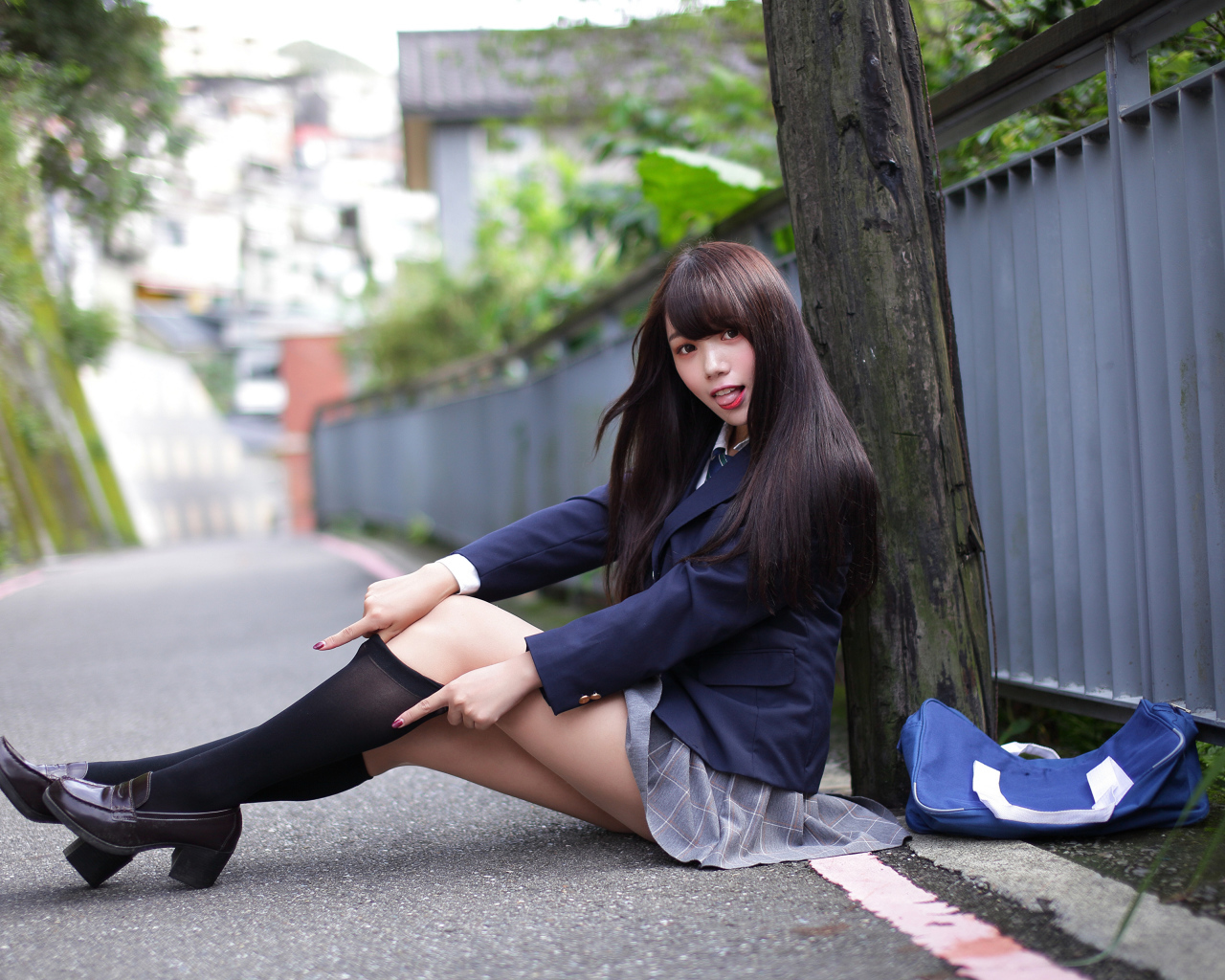 Девушка азиатка в черных чулках сидит у дерева