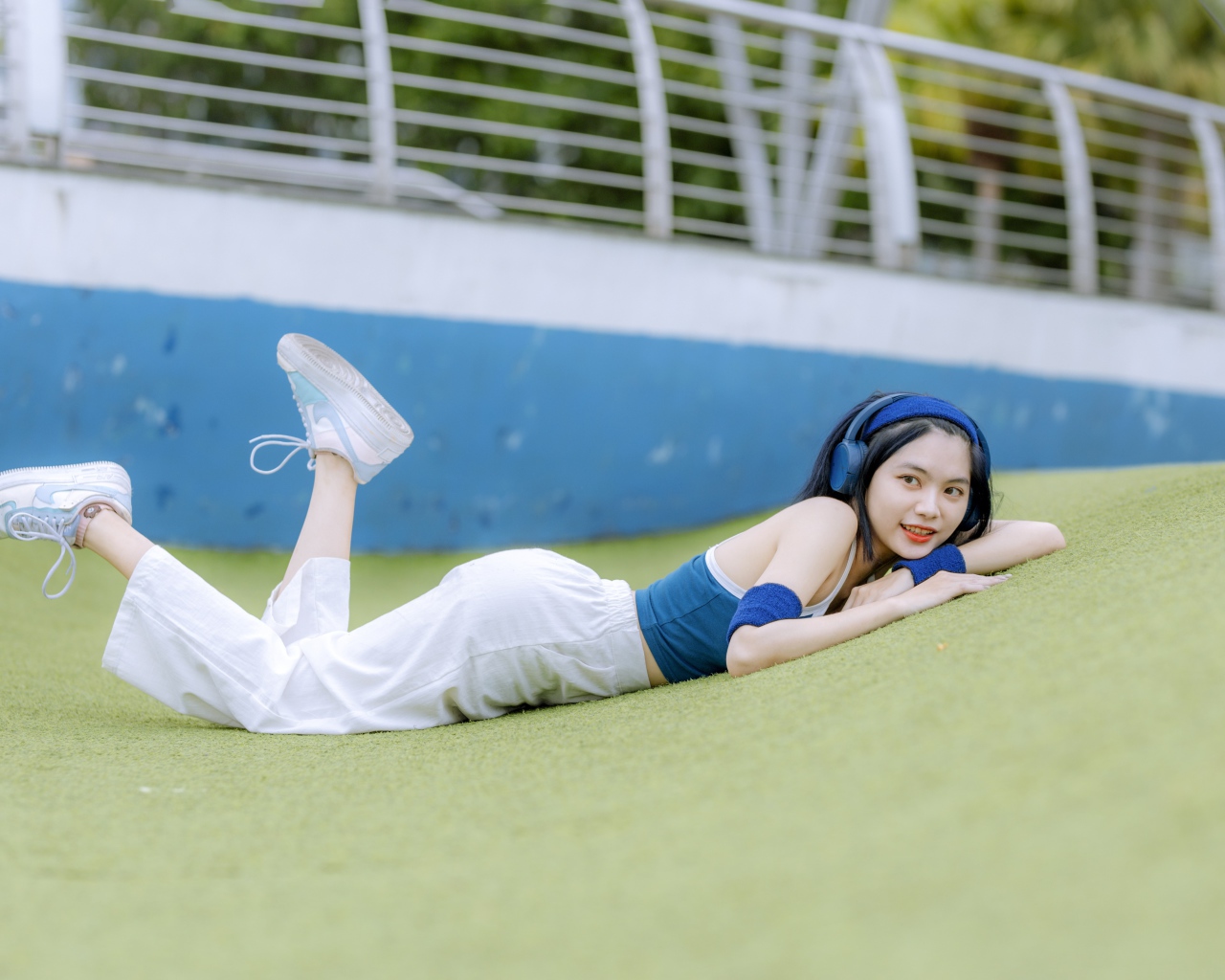 Девушка азиатка в наушниках лежит на полу 