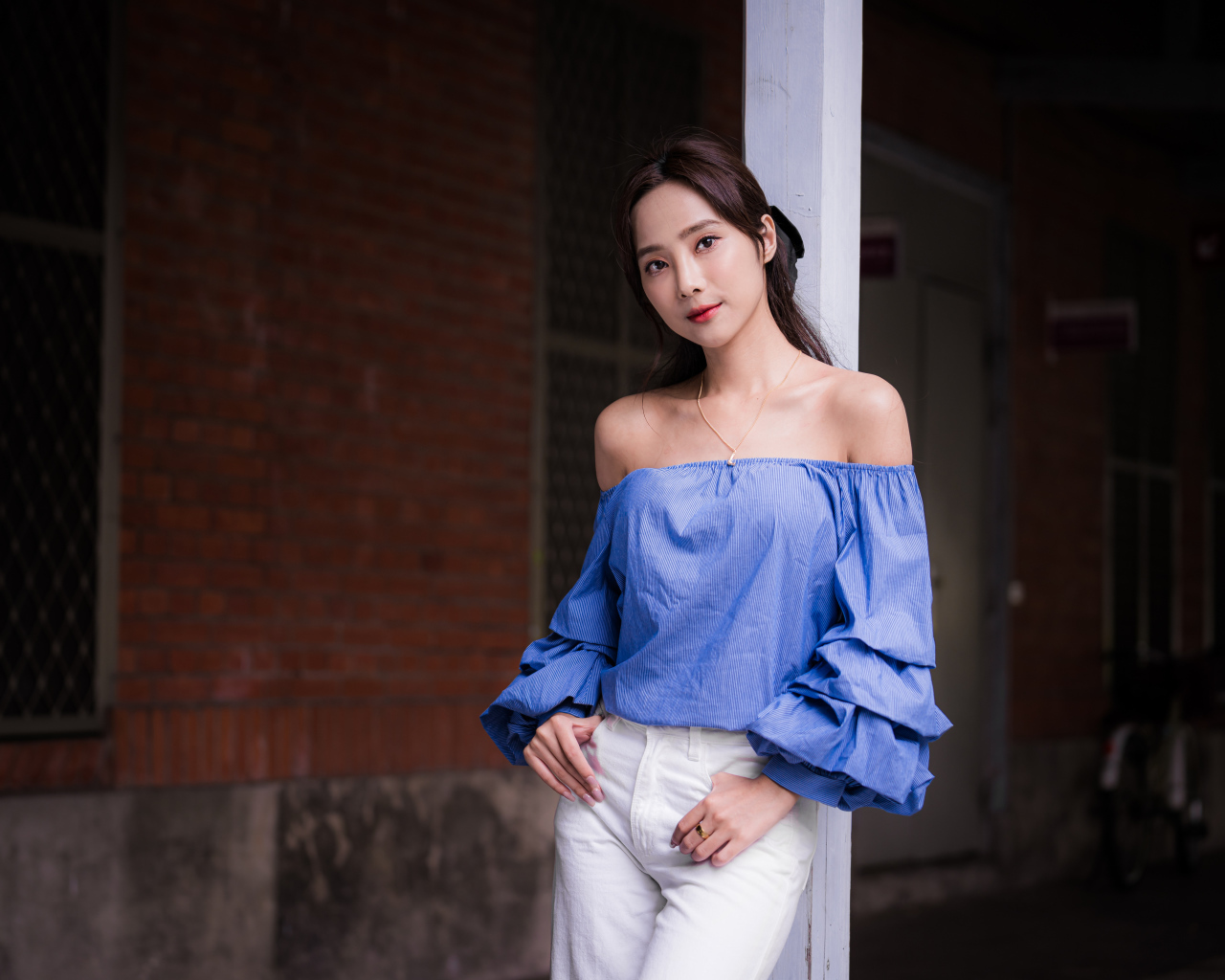 Девушка азиатка в белых брюках у дома