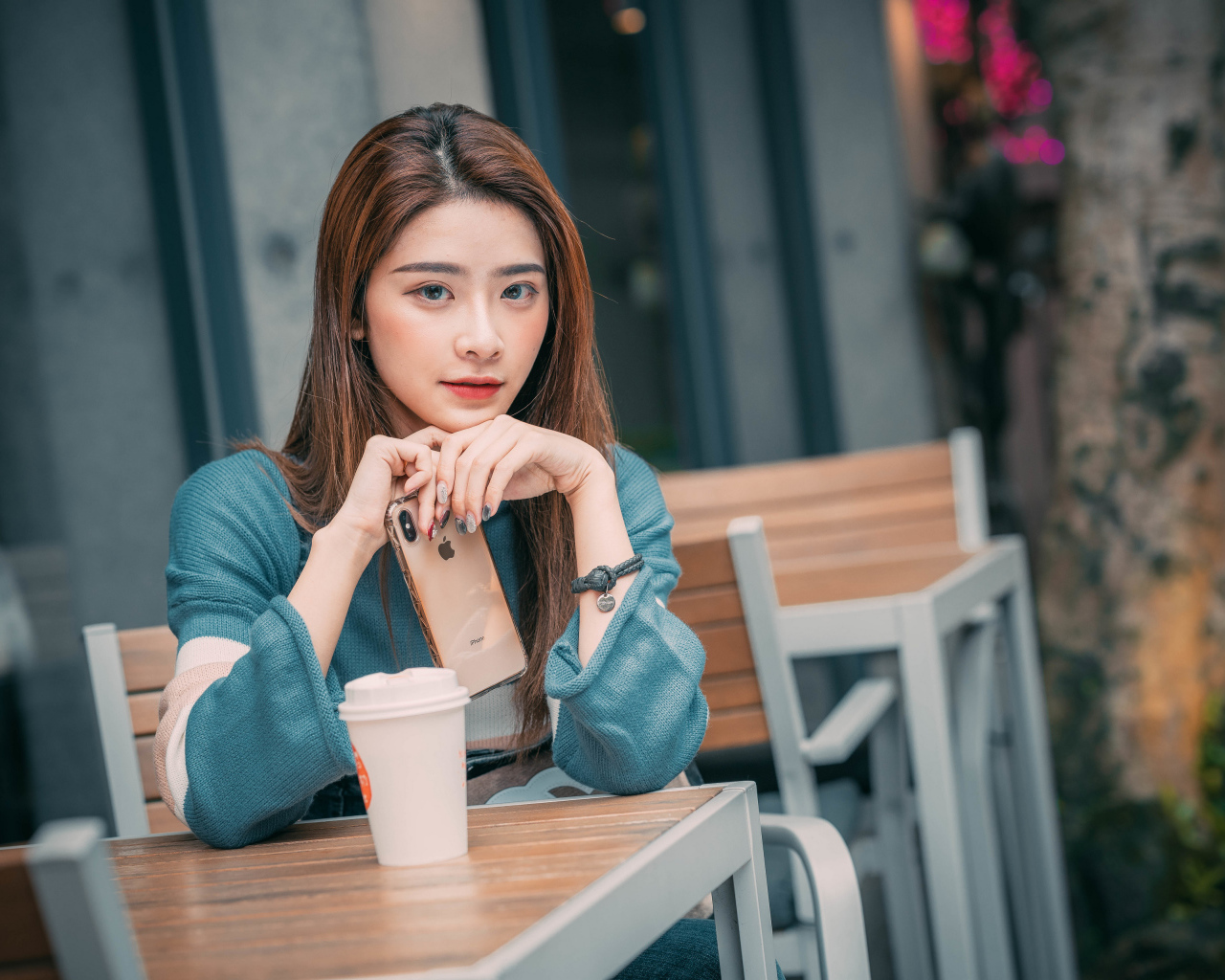 Девушка азиатка сидит за столом в кафе с телефоном 