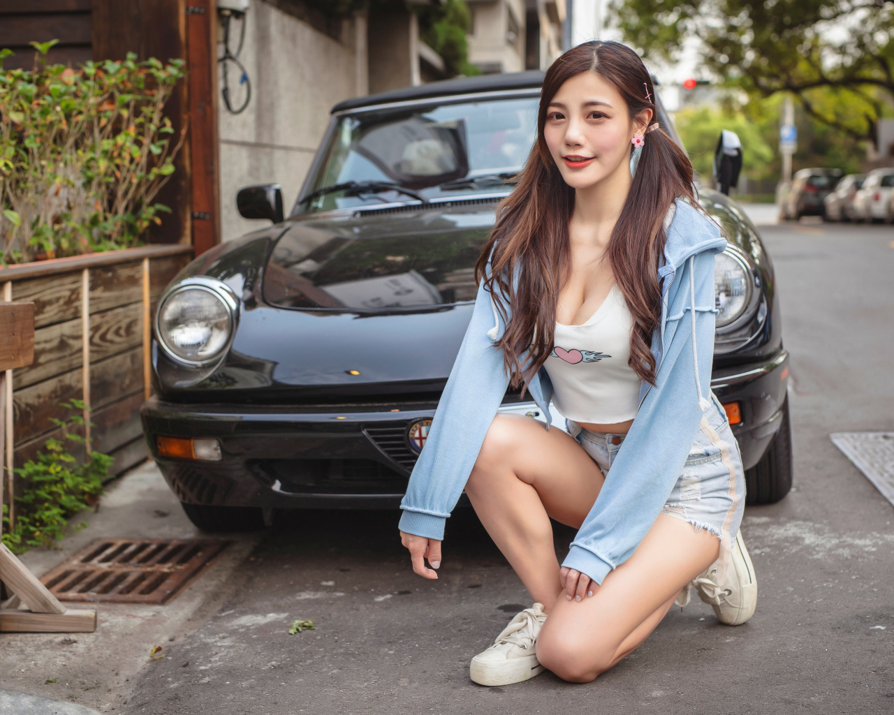 Девушка азиатка сидит возле машины 