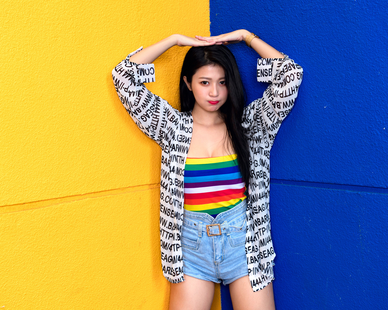 Девушка азиатка стоит у двухцветной стены