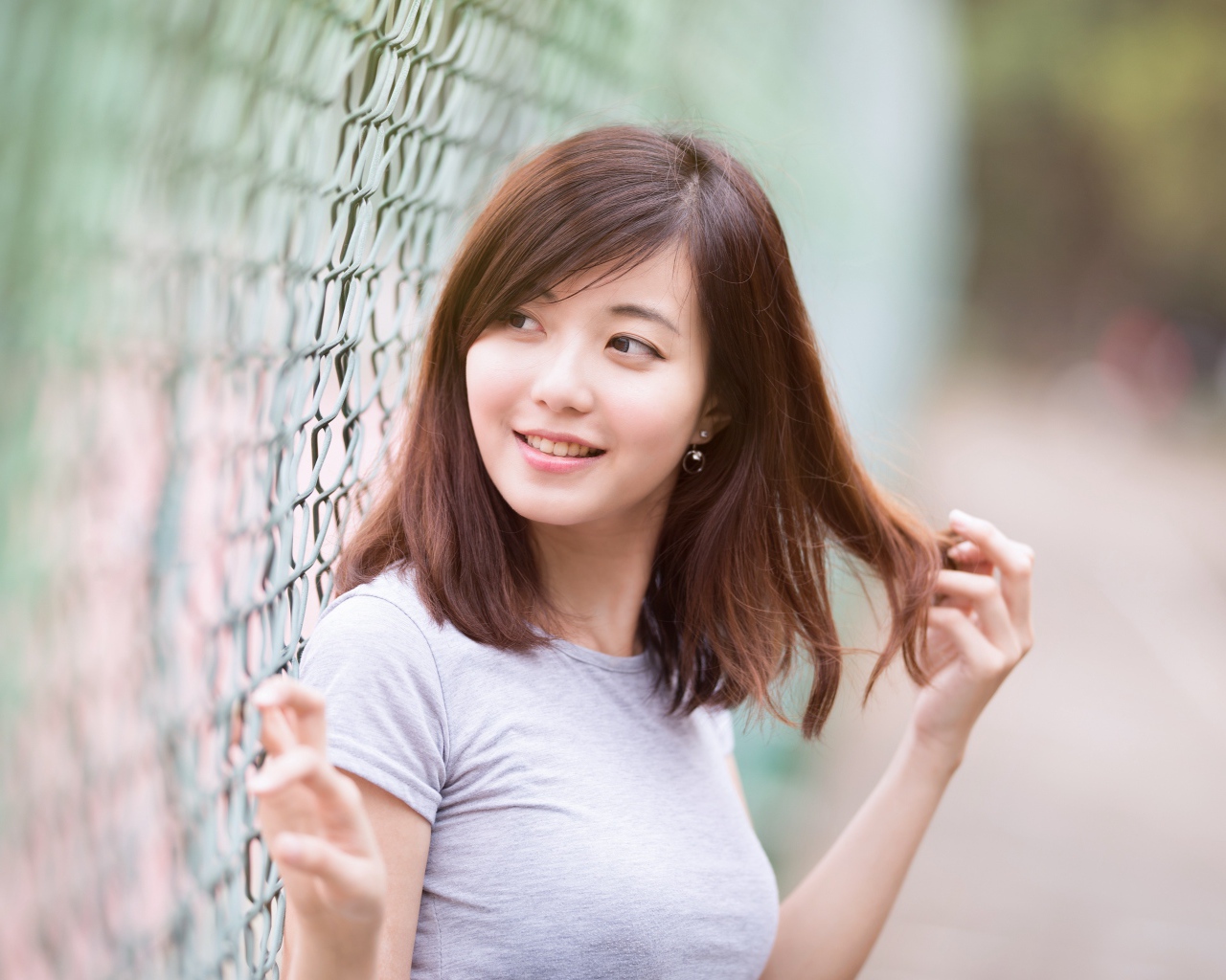 Девушка азиатка с милой улыбкой стоит у сетки 