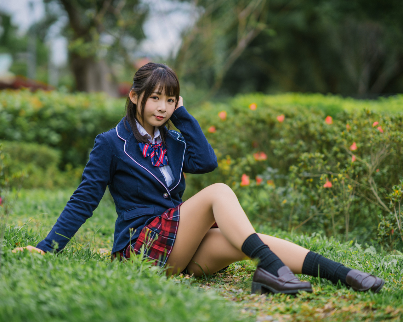 Азиатская школьница сидит на траве