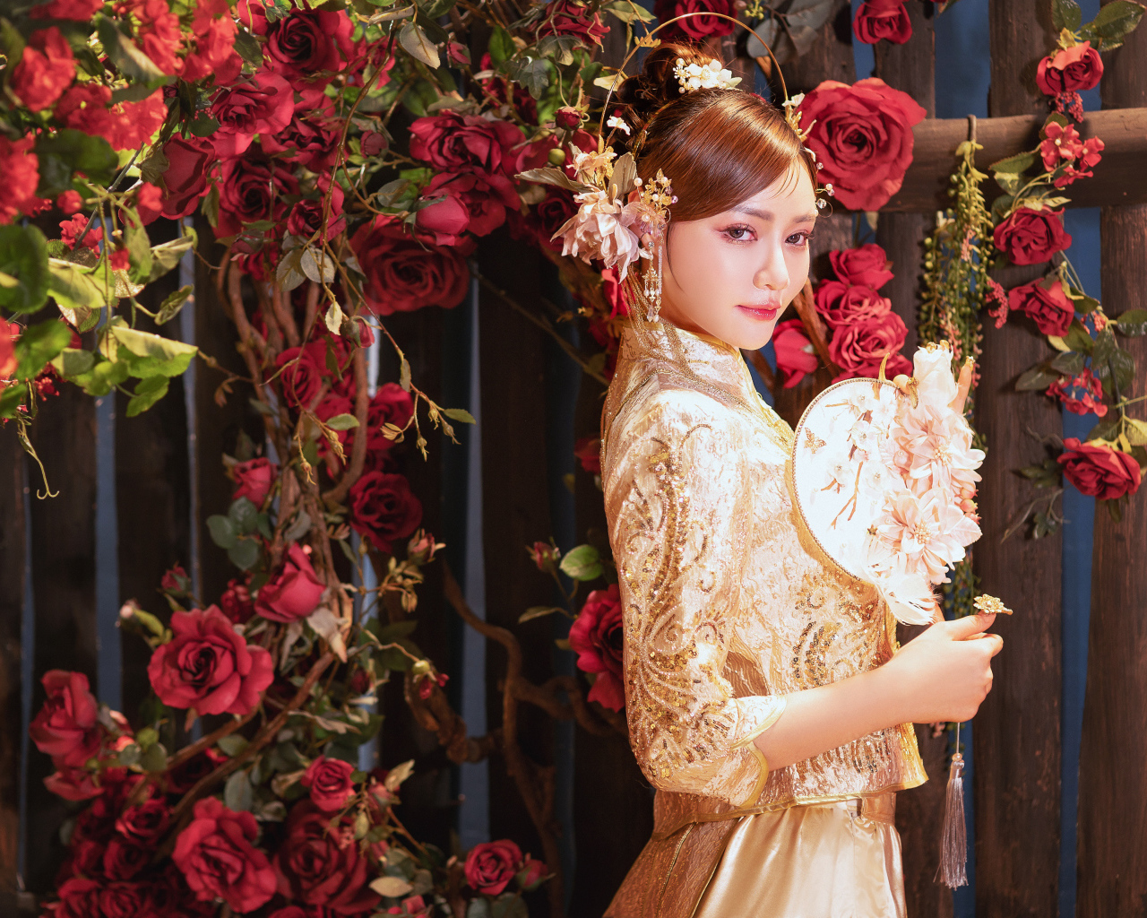 Азиатка в красивом национальном костюме у куста роз