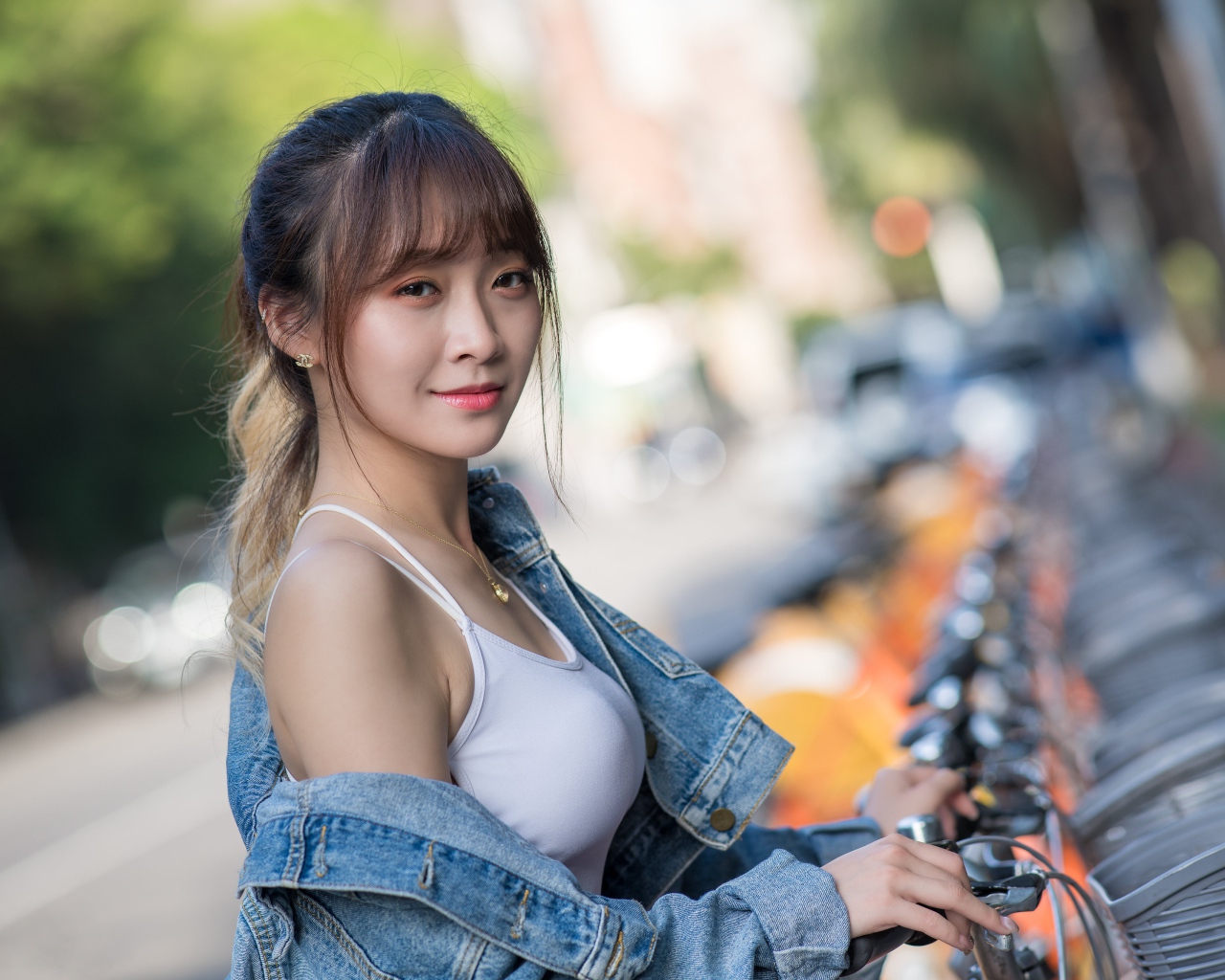 Красивая азиатка в джинсовой куртке с велосипедом