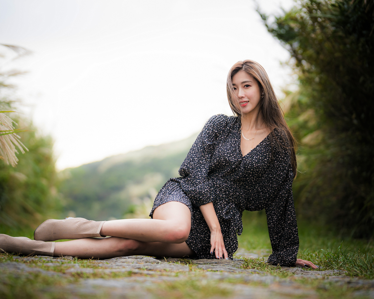 Красивая девушка азиатка в платье лежит на земле 