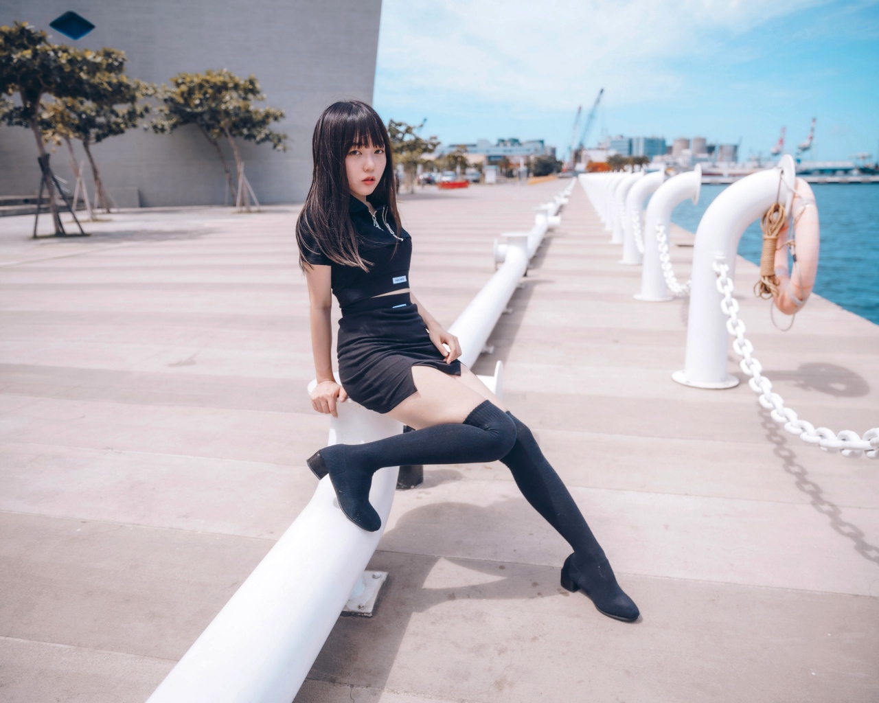 Красивая девушка азиатка в черных сапогах на причале