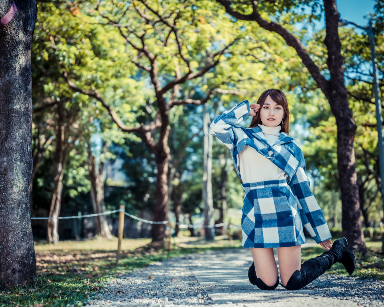 Красивая девушка азиатка стоит на коленях в парке