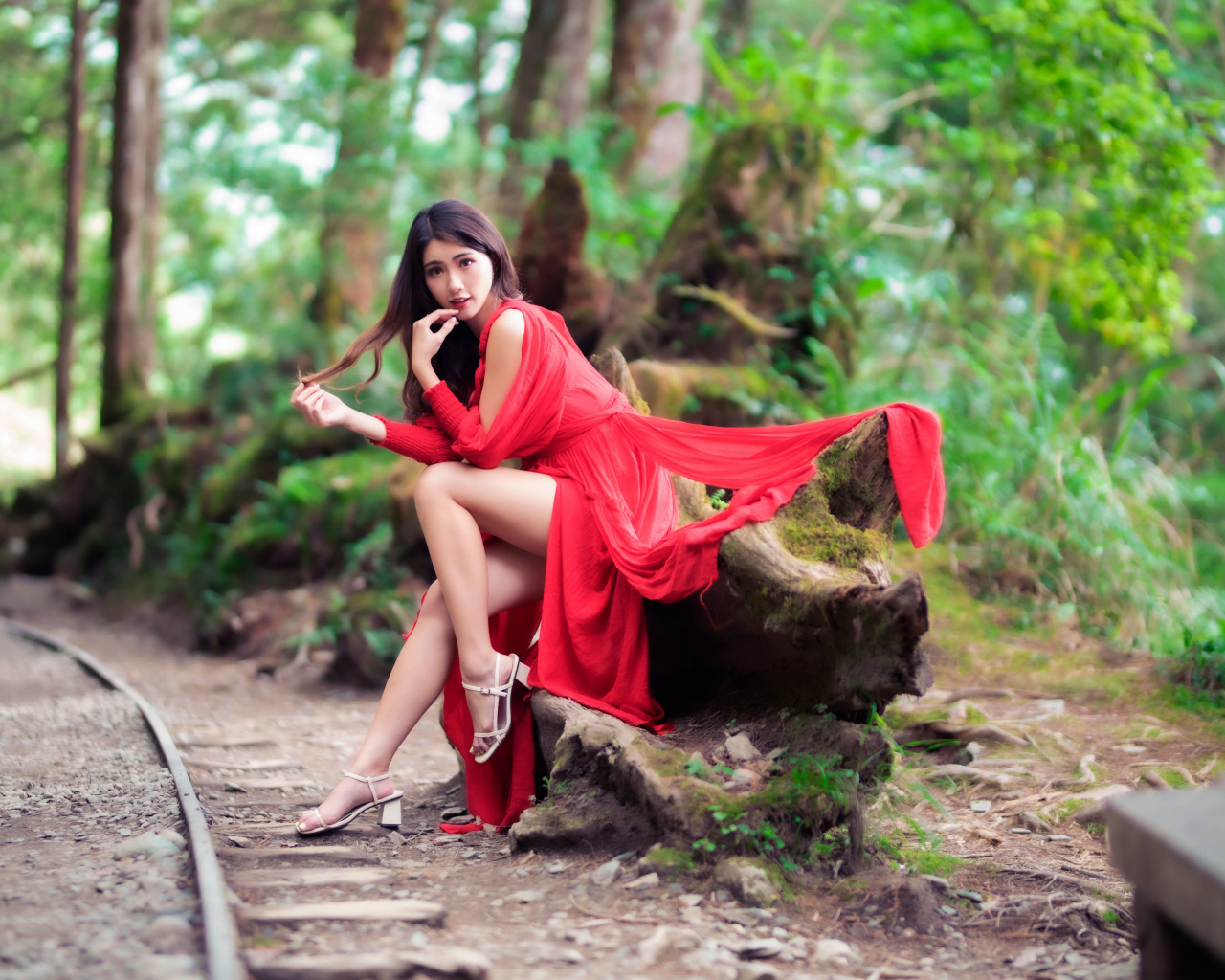 Красивая азиатка в красном платье сидит на дереве 