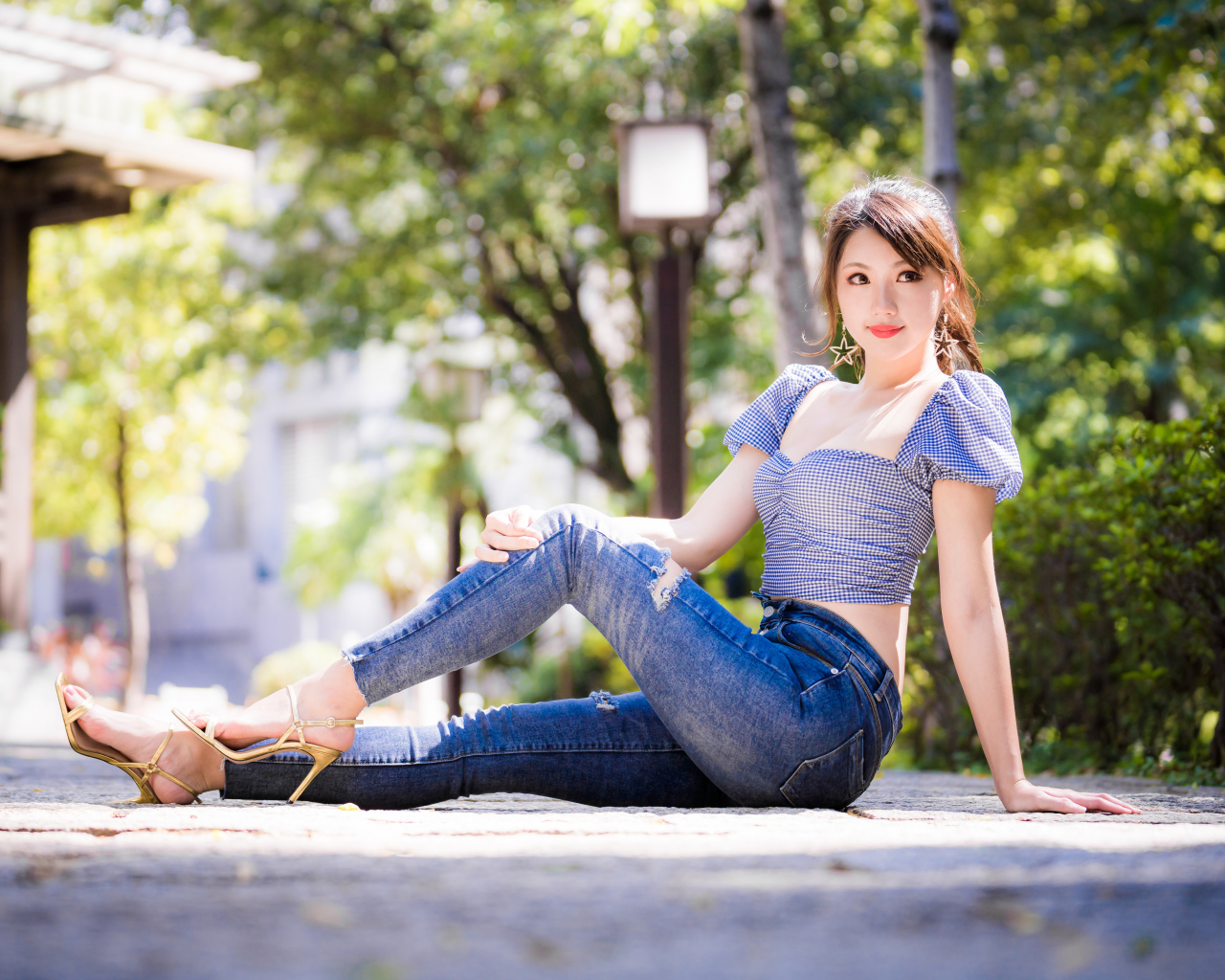 Красивая азиатка в джинсах сидит на земле