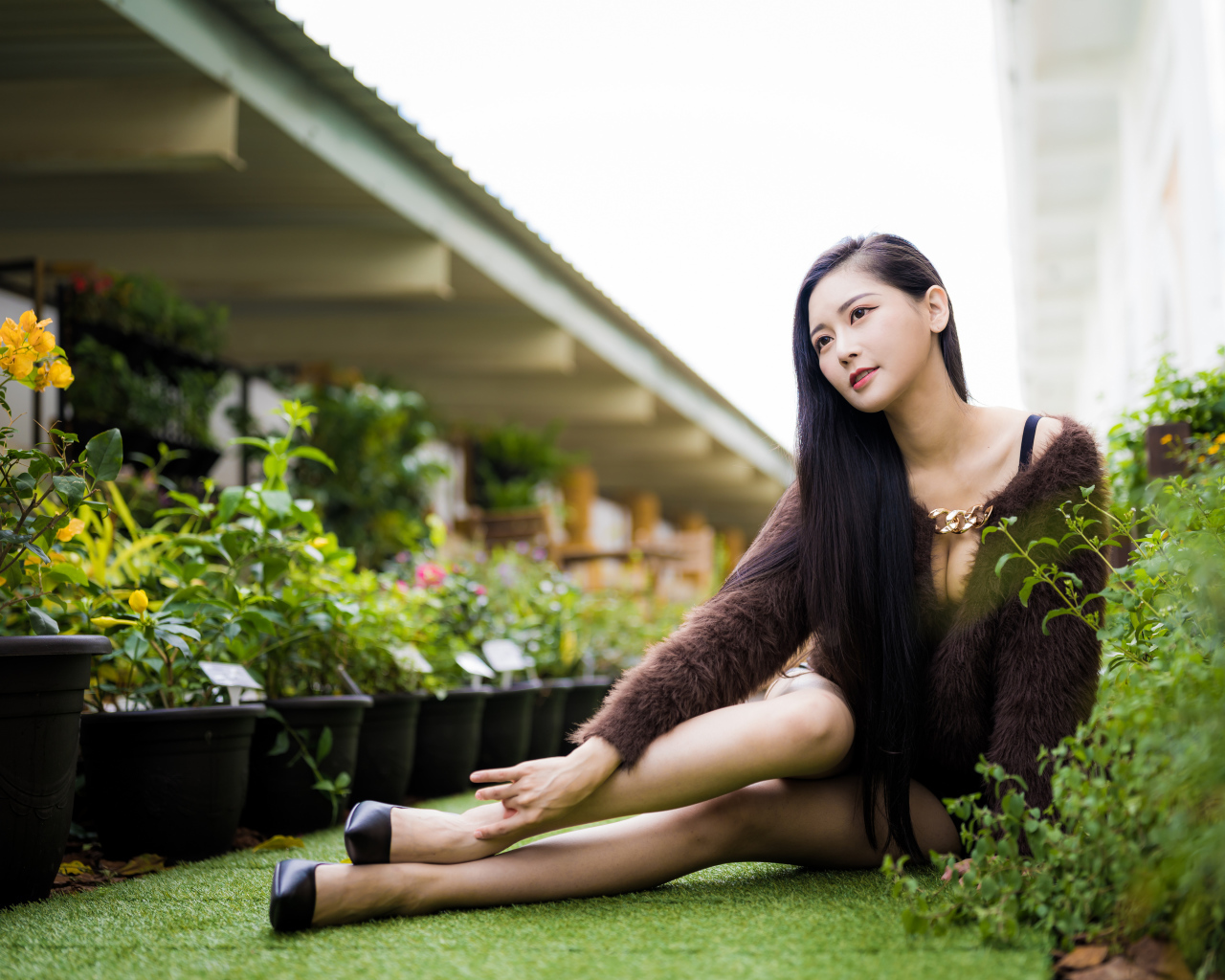 Красивая азиатка сидит на земле у цветов