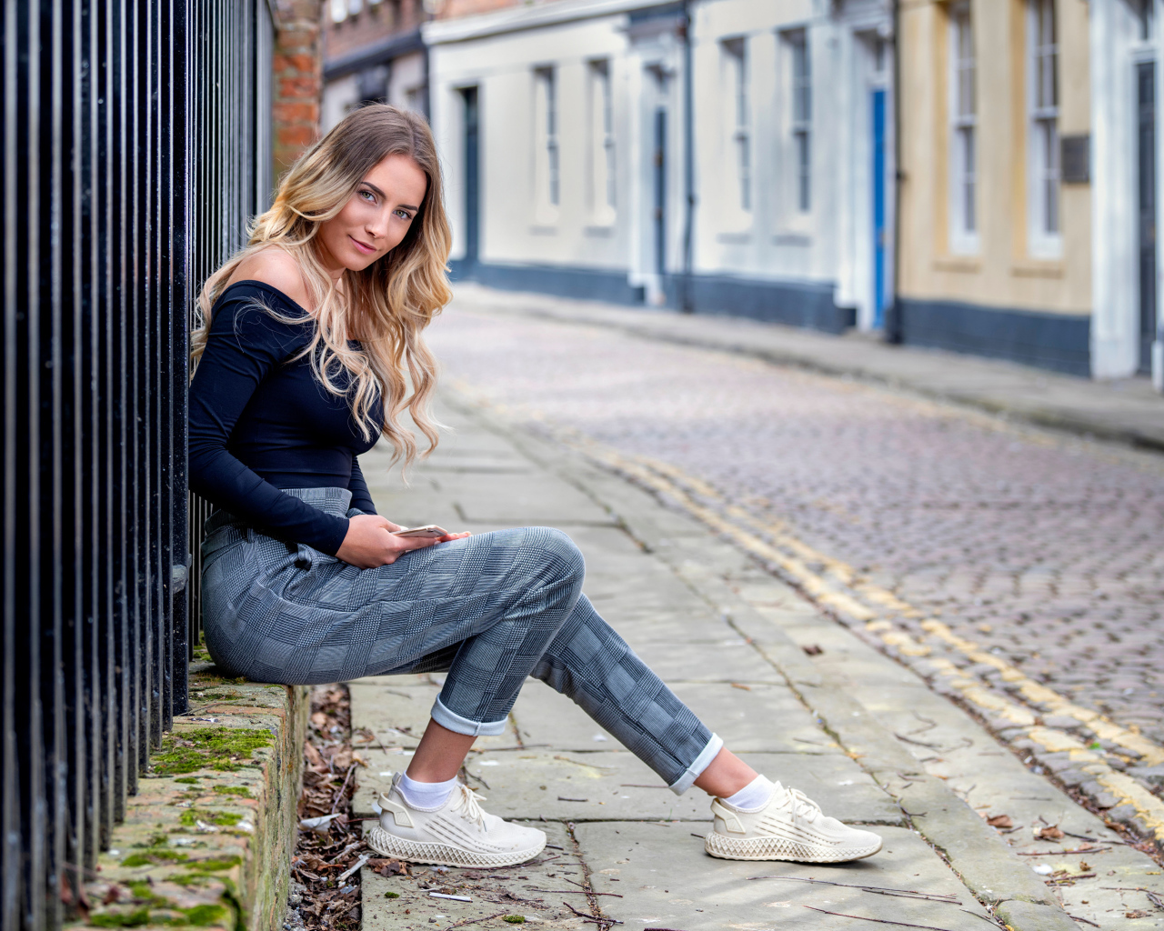 Красивая девушка блондинка сидит у забора