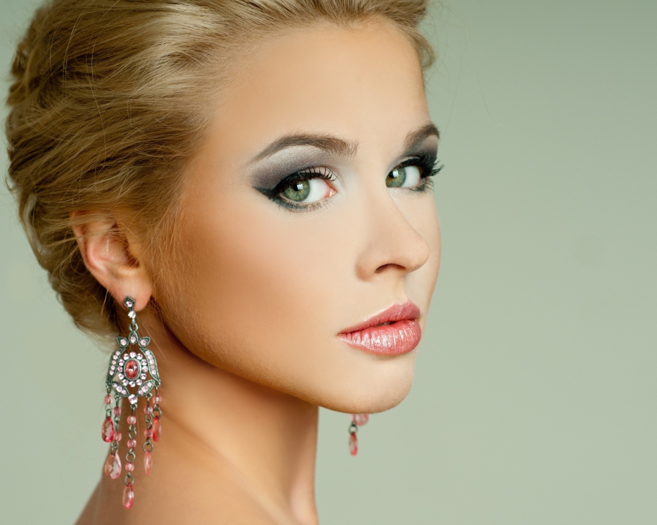 Красивая девушка блондинка с красивыми сережками на сером фоне