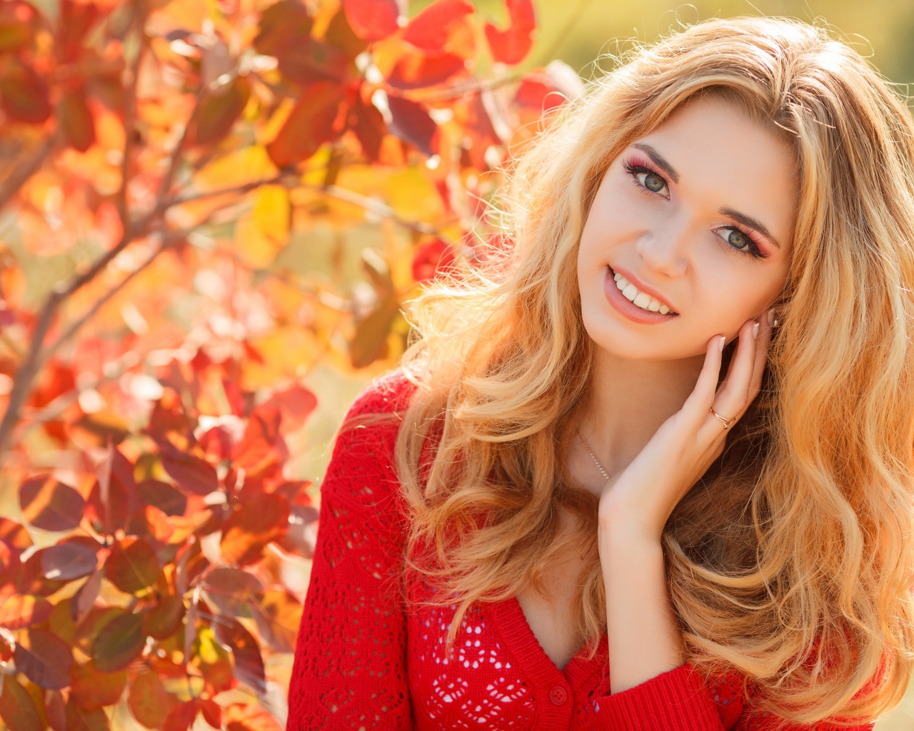 Красивая блондинка в красной кофте на улице осенью 