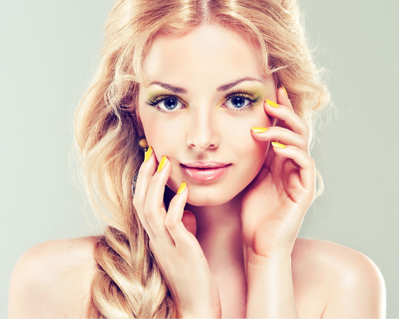 Красивая голубоглазая блондинка с желтым маникюром на руках 