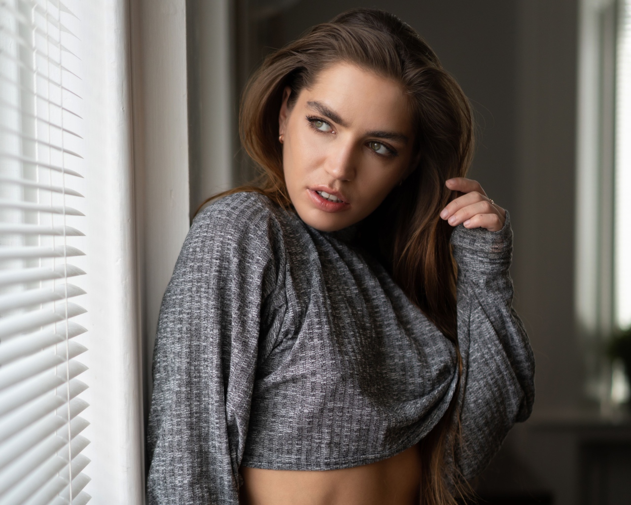 Красивая девушка брюнетка стоит у окна