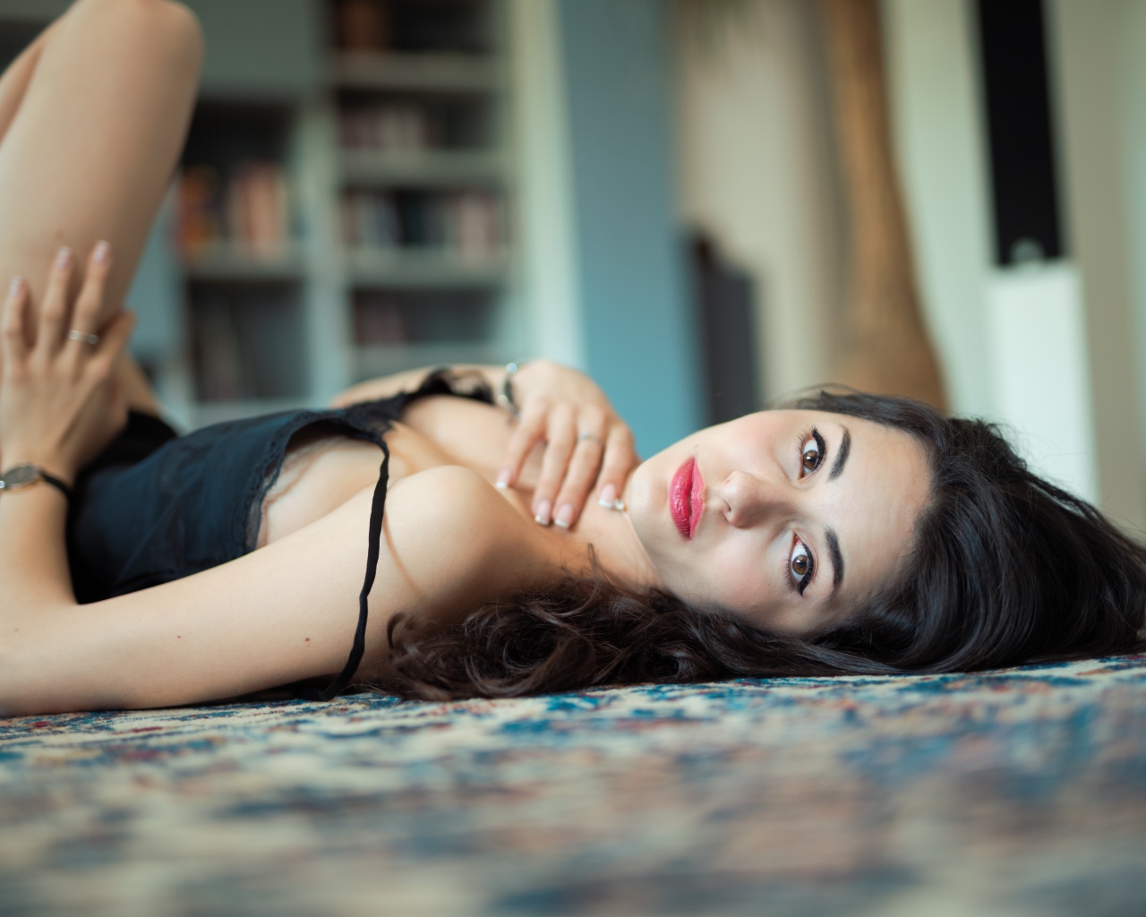 Красивая брюнетка в черном платье лежит на полу