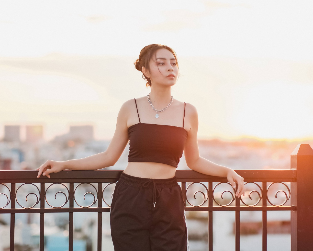 Красивая девушка в черном костюме на мосту в лучах солнца