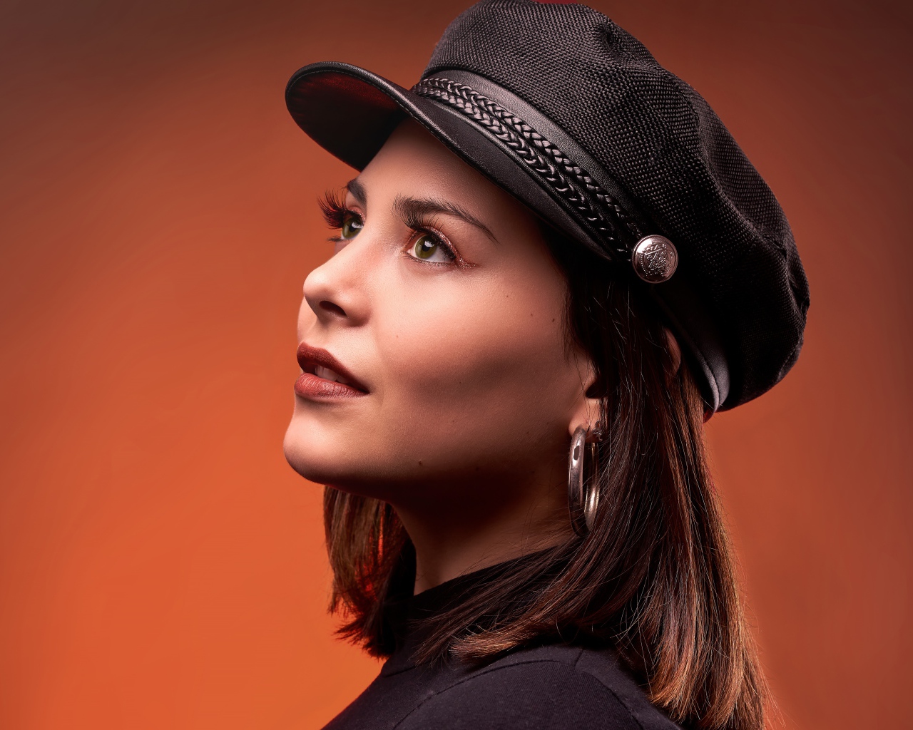 Красивая девушка в кепке на коричневом фоне