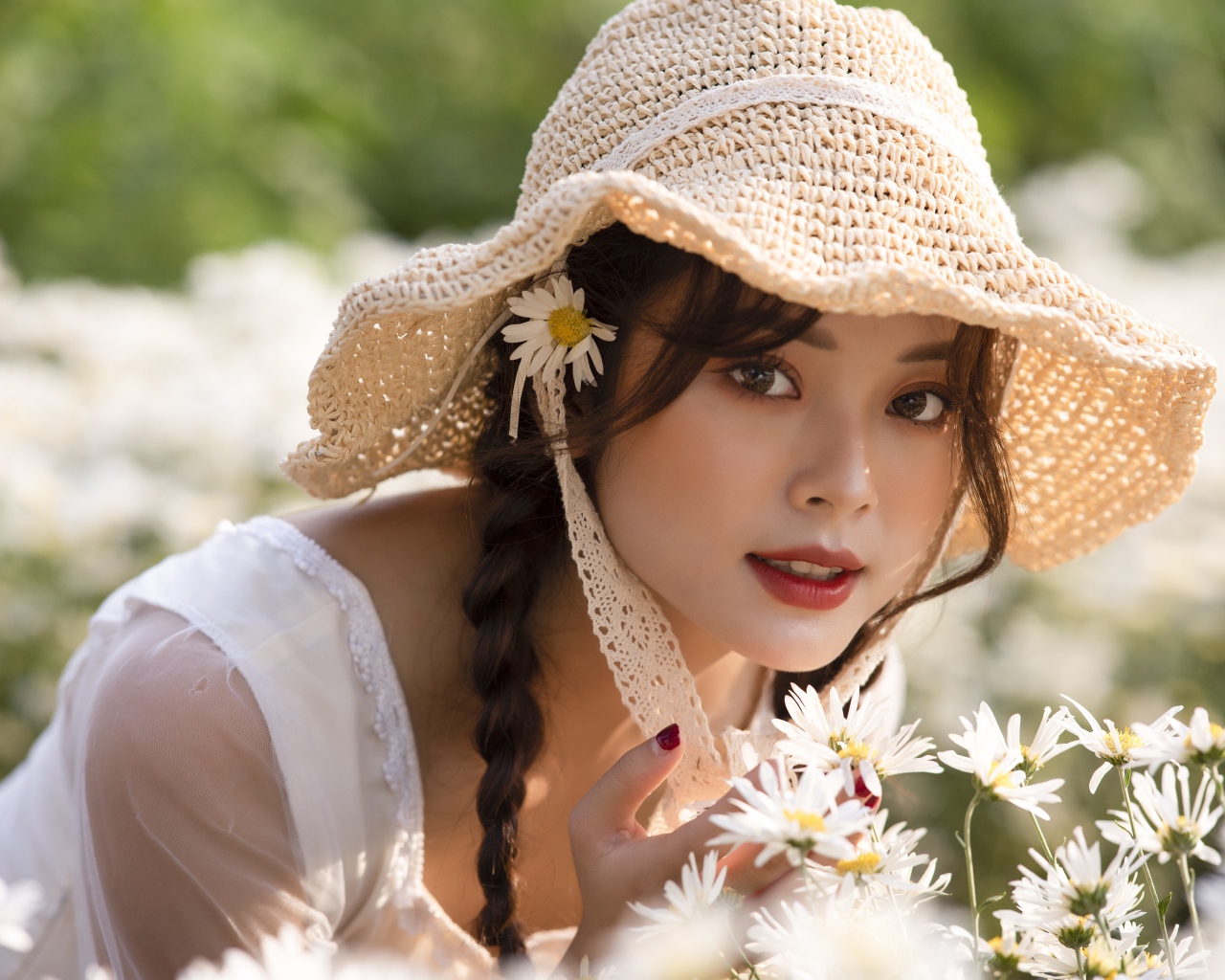 Красивая девушка в шляпе на поле с ромашками 