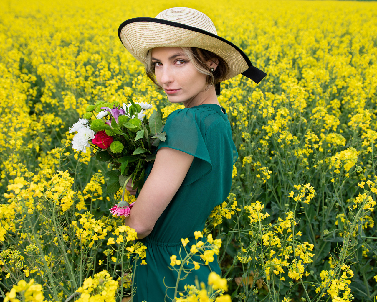 Красивая девушка в шляпе на поле с желтыми цветами летом