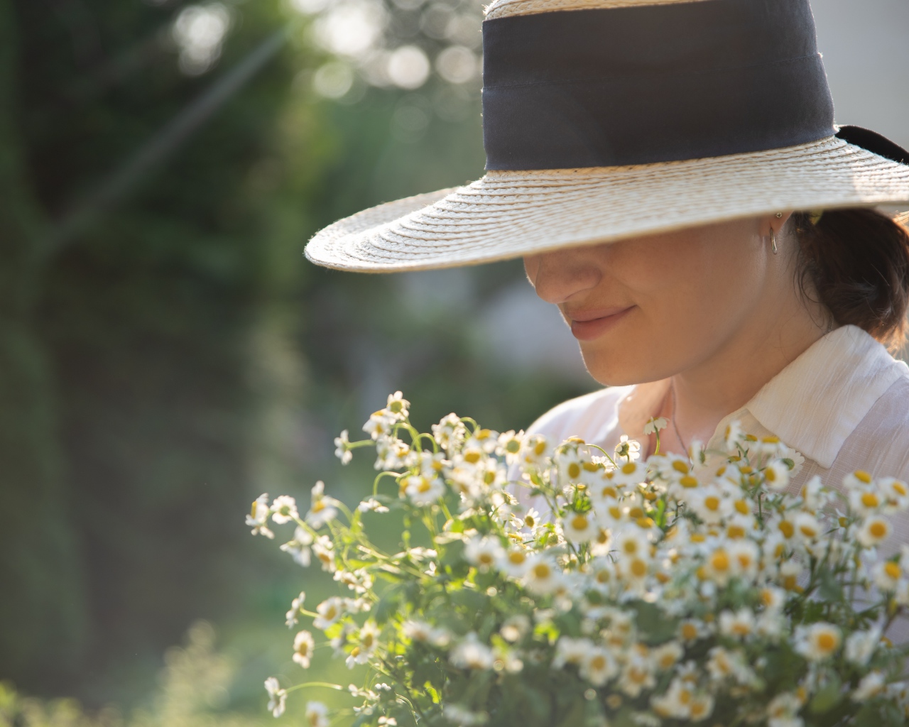 Красивая девушка в шляпе с букетом ромашек 
