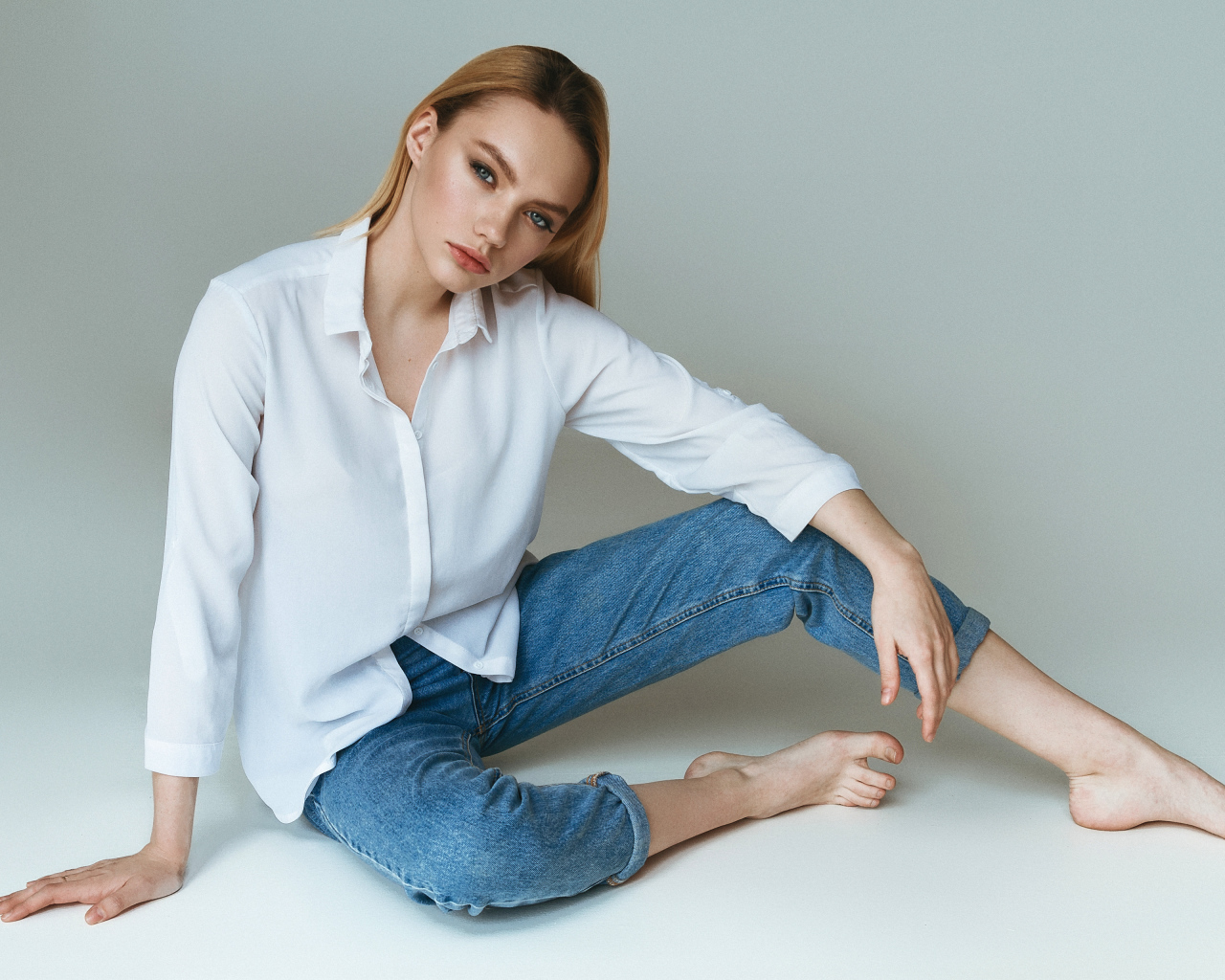 Красивая девушка в белой рубашке на сером фоне