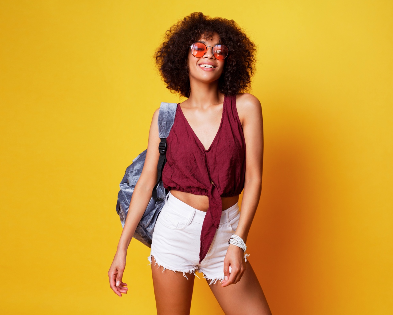 Красивая девушка в очках с рюкзаком на желтом фоне 