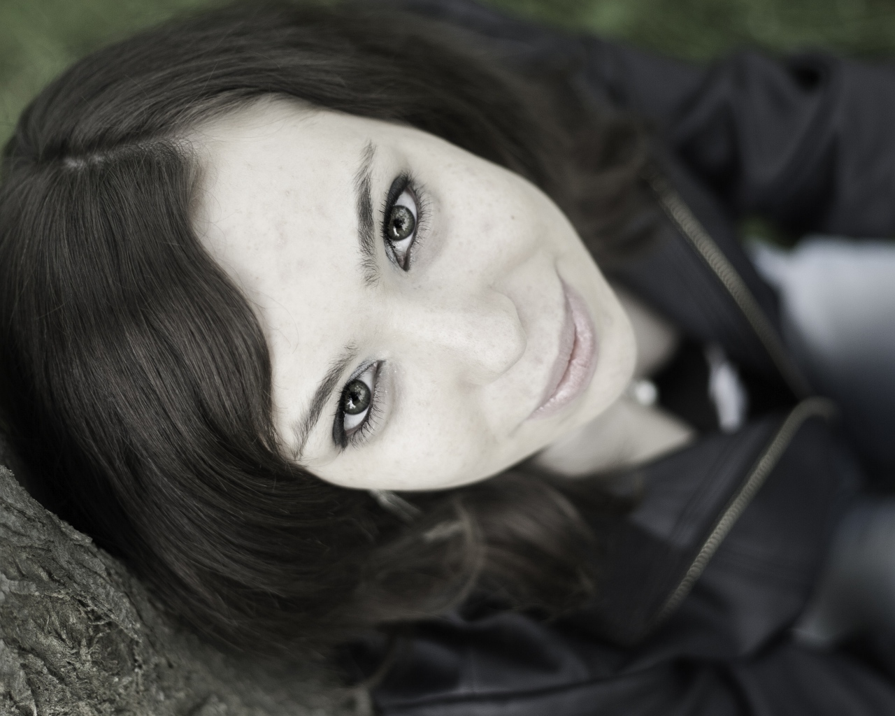 Красивая девушка смотрит вверх сидя под деревом  